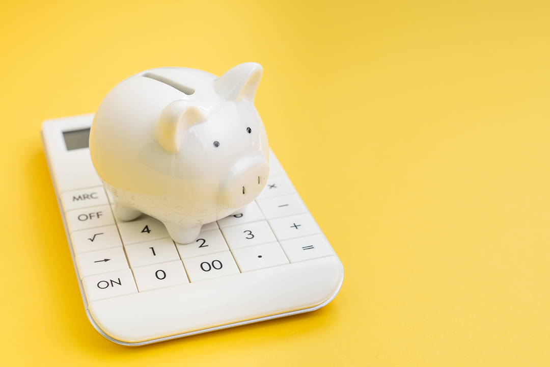 A piggy bank on top of a calculator